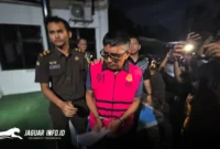 Tersangka IKM (tengah) tampak keluar dari ruang penyidik Kejaksaan Tinggi Sulawesi Utara dengan mengenakan rompi tahanan berwarna merah, Jumat (27/2/2026). Foto Istimewa