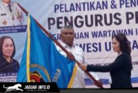 Ketua PWI Sulawesi Utara, Sintya Bojoh, menyerahkan pataka organisasi kepada Hut Kamrin dalam acara pelantikan di Manado.