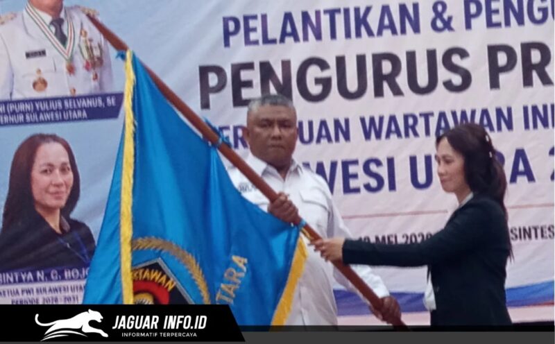 Ketua PWI Sulawesi Utara, Sintya Bojoh, menyerahkan pataka organisasi kepada Hut Kamrin dalam acara pelantikan di Manado.