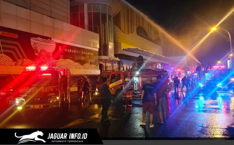 Petugas pemadam kebakaran saat berupaya memadamkan kobaran api di area luar gedung pusat perbelanjaan.