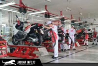 Ilustrasi mekanik bengkel sedang memeriksa kondisi shockbreaker sepeda motor untuk memastikan kenyamanan berkendara.