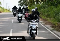 Ilustrasi pengendara motor menggunakan helm bervisual tertutup dan masker sebagai perlengkapan keselamatan saat menghadapi hujan abu vulkanik di jalan raya.