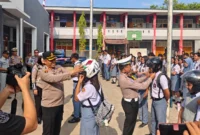 Kapolres Minahasa Tenggara AKBP Handoko Sanjaya bersama Kasatlantas Iptu Nicky Pondalos saat berbagi helm berstandar SNI kepada siswa SMKN 1 Ratahan, 27/10/2026.