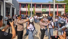 Kapolres Minahasa Tenggara AKBP Handoko Sanjaya bersama Kasatlantas Iptu Nicky Pondalos saat berbagi helm berstandar SNI kepada siswa SMKN 1 Ratahan, 27/10/2026.