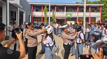 Kapolres Minahasa Tenggara AKBP Handoko Sanjaya bersama Kasatlantas Iptu Nicky Pondalos saat berbagi helm berstandar SNI kepada siswa SMKN 1 Ratahan, 27/10/2026.